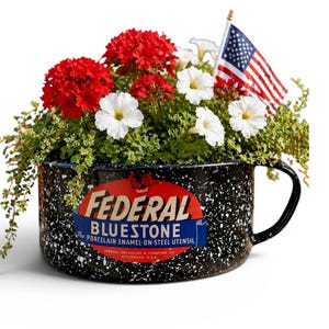 May include: A black and white speckled enamelware mug filled with red and white flowers and greenery, with a small American flag. The mug has a handle and a label that reads "FEDERAL BLUESTONE".