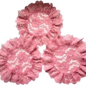 May include: Three pink lace doilies with a floral pattern and ruffled edges are displayed against a white background. The doilies are circular and appear to be made of delicate, sheer fabric. The overall aesthetic is vintage and feminine.