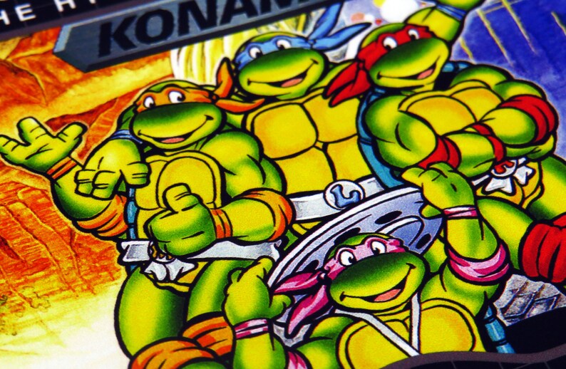 Może przedstawiać: Cztery postacie z kresk&oacute;wek Teenage Mutant Ninja Turtles w stylu komiksowym. Ż&oacute;łwie są zielone z pomarańczowymi i ż&oacute;łtymi akcentami. Ż&oacute;łwie noszą chusty w r&oacute;żnych kolorach. Tło to ż&oacute;łty i pomarańczowy krajobraz.