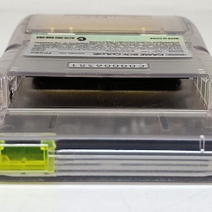 Puede incluir: Un cartucho transparente de Game Boy Color con un mecanismo de bloqueo amarillo. El cartucho tiene una etiqueta con texto y un n&uacute;mero de serie. La Game Boy Color es un dispositivo de juego port&aacute;til.