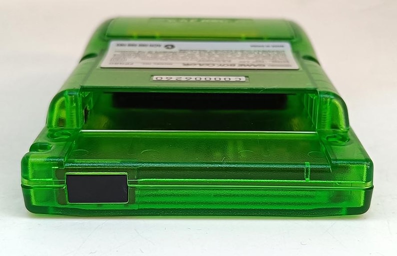Puede incluir: Un cartucho de Game Boy Color verde transparente. El cartucho tiene forma rectangular con una ranura para el juego. La parte posterior del cartucho tiene una etiqueta blanca con texto y un n&uacute;mero de serie. El cartucho est&aacute; hecho de pl&aacute;stico.