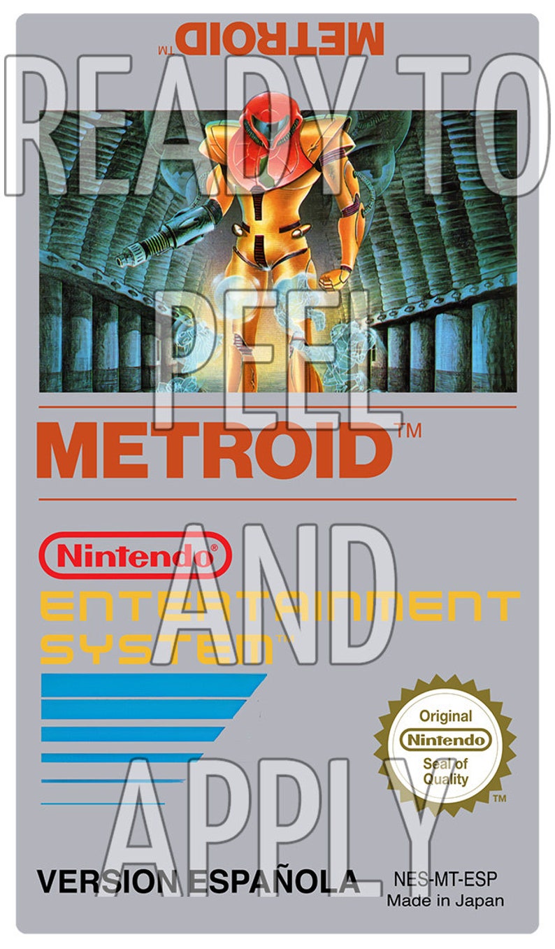 Może przedstawiać: Wkład do gry wideo vintage do konsoli Nintendo Entertainment System. Wkład jest szary z czerwoną i ż&oacute;łtą etykietą z napisem "Metroid" i przedstawia postać w ż&oacute;łtym i czerwonym stroju trzymającą broń. Etykieta zawiera r&oacute;wnież tekst "Ready to Play" i "Version Espa&ntilde;ola".