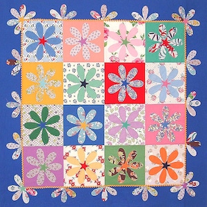 Puede incluir: Una colcha azul con un diseño de patchwork que presenta varios patrones florales en tonos de rosa, rojo, verde, amarillo y azul. La colcha está bordeada con una fila de formas de flores azules.
