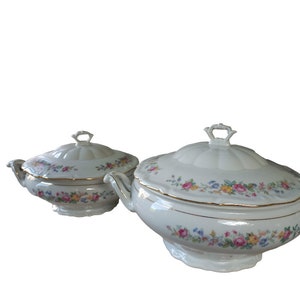 Könnte beinhalten: Zwei weiße Porzellanservierplatten mit Blumenmustern und goldenen Akzenten. Die Platten haben Deckel und sind perfekt zum Servieren einer Mahlzeit.