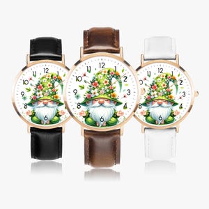 May include: Three wristwatches with gold-coloured cases and white faces. Each watch has a gnome design with a green floral hat in a meditative pose. The straps are black, brown, and white.