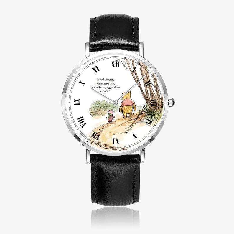 Pode incluir: Um rel&oacute;gio de pulso com uma pulseira de couro preta e uma caixa prateada. O mostrador do rel&oacute;gio apresenta uma ilustra&ccedil;&atilde;o de Winnie the Pooh com a cita&ccedil;&atilde;o: "How lucky am I to have something that makes saying good-bye so hard."