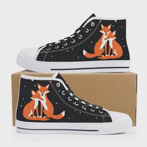 Op de afbeelding: Een paar zwarte high-top canvas schoenen met een witte zool. De schoenen hebben een sterrenhemelontwerp met twee knuffelende oranje vossen.