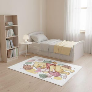 Peut inclure: Un tapis rectangulaire blanc avec une illustration de dessin animé de Winnie l'Ourson et Porcinet se câlinant. Le tapis présente un design coloré avec des formes pastel et des accents floraux. Le tapis est dans une chambre.