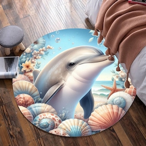 May include: A round rug featuring a detailed illustration of a dolphin. The dolphin is light gray and white, with a blue ocean background. Seashells and starfish surround the dolphin, with a beach scene in the distance. The rug is a decorative floor covering.