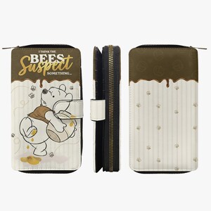 Könnte beinhalten: Eine Geldbörse im Winnie-the-Pooh-Design mit Reißverschluss. Auf der Vorderseite ist Winnie Puuh mit Honig und dem Text "I THINK THE BEES SUSPECT SOMETHING..." abgebildet. Die Geldbörse hat ein weißes und braunes Farbschema mit Bienen- und Honigtropfen-Details.