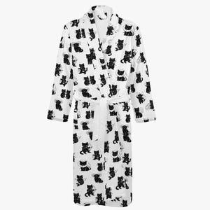 May include: White bathrobe featuring a repeating pattern of black cat illustrations. The robe has long sleeves, a shawl collar, and a matching belt. The cats are depicted in various poses, adding a playful touch to the comfortable garment.