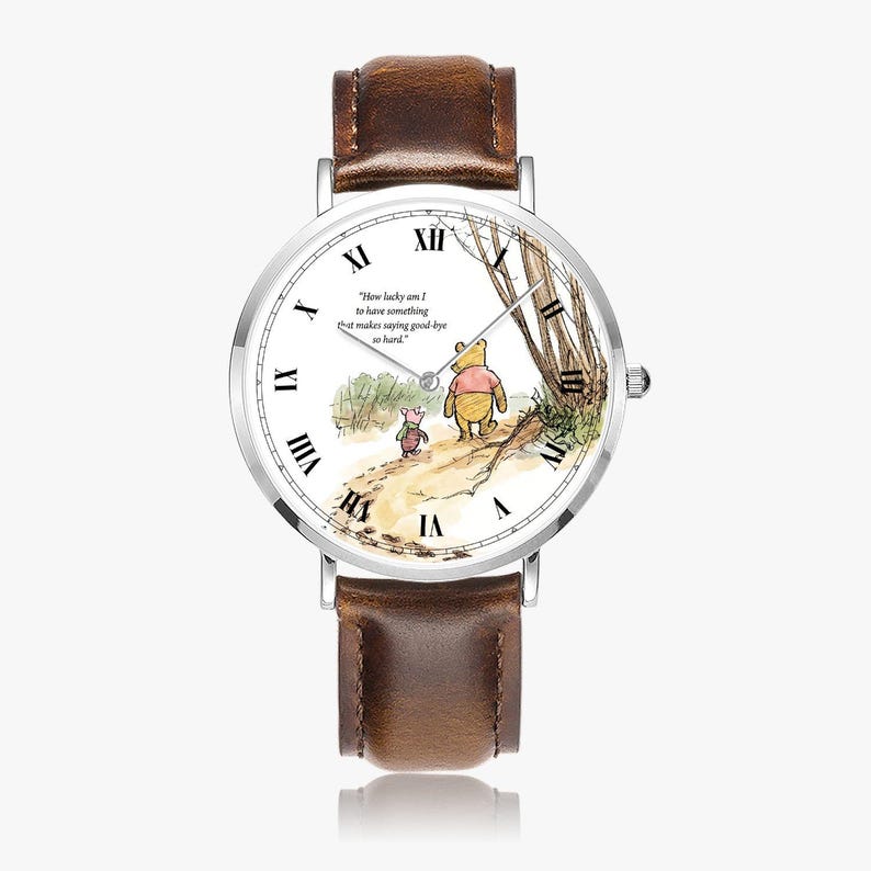 Pode incluir: Um rel&oacute;gio de pulso com pulseira de couro castanho e mostrador branco. O mostrador apresenta uma ilustra&ccedil;&atilde;o em aquarela de Winnie the Pooh e Piglet caminhando em um caminho, com a cita&ccedil;&atilde;o "How lucky am I to have something that makes saying good-bye so hard."