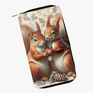 Könnte beinhalten: Eine Geldbörse mit einer detaillierten Illustration von zwei Eichhörnchen, die sich an den Händen halten. Die Eichhörnchen sind vor einem floralen Hintergrund mit Reißverschluss platziert. Die Geldbörse hat einen schwarzen Rand und einen Magnetverschluss.