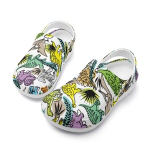 Bunte Dinosaurier Clogs – Lustige Slip-On Sandalen für Damen, Herren und Kinder – Hausschuhe und Gartenschuhe Dino-Motiv, Cartoon-Design