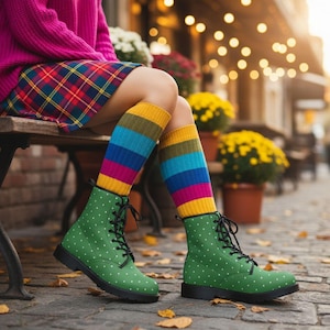 Könnte beinhalten: Grüne Kampfstiefel mit weißen Punkten, schwarzen Schnürsenkeln und Sohlen. Die Stiefel werden mit bunten gestreiften Socken und einem karierten Rock kombiniert. Das Outfit wird durch einen rosa Pullover ergänzt.