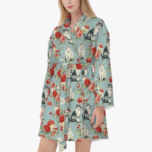 May include: A light blue robe with a floral print featuring cats and flowers. The robe has a tie belt and long sleeves.