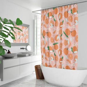 Pu&ograve; includere: Una tenda da doccia rosa con un motivo di fette d'arancia e foglie verdi. La tenda da doccia &egrave; appesa in un bagno con una vasca da bagno bianca e un mobile da bagno bianco.