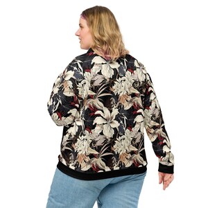 May include: A black sweatshirt with a floral print featuring white, red, and beige flowers. The sweatshirt has long sleeves and a crew neck.