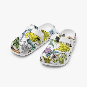 Tamancos coloridos de dinossauro – sandálias divertidas para mulheres, homens e crianças – chinelos e sapatos de jardim com motivo de dinossauro e design de desenho animado