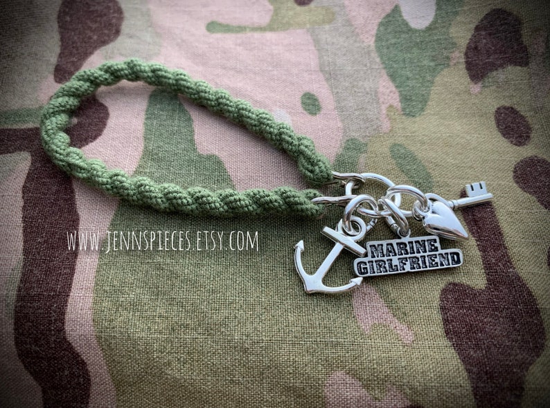 May include: A green paracord bracelet with a silver charm that says "Marine Girlfriend" and includes an anchor, a heart, and a key.