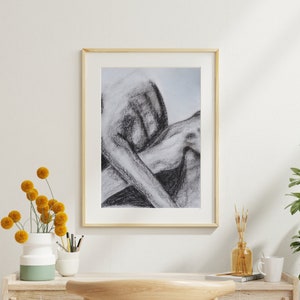 May include: A black and white charcoal drawing of a person in a seated pose, framed in a light wood frame.