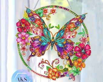 Puede incluir: Un atrapasoles de mariposa colorido con un marco circular, adornado con flores vibrantes. La mariposa presenta tonos de azul, morado y rosa. El atrapasoles cuelga de una cadena plateada, agregando un toque decorativo a cualquier ventana.