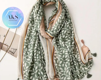 May include: A green and white leaf-patterned scarf with a beige border and tassels. The scarf has a light pink stripe and is draped on a white surface. The text "AKS AnyKinds Store" is in a blue circle.