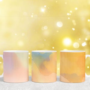 Puede incluir: Tres tazas de cer&aacute;mica con dise&ntilde;os abstractos de acuarela. Las tazas son en tonos de rosa, amarillo y naranja.