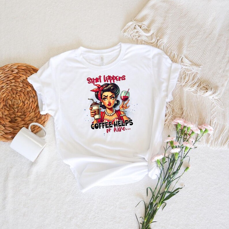 Puede incluir: Camiseta blanca con una ilustraci&oacute;n retro de una mujer sosteniendo caf&eacute; y una copa de vino. El texto de la camiseta dice: "Shit Happens Coffee Helps or Wine..." La mujer de la ilustraci&oacute;n tiene cabello oscuro y lleva una diadema roja.