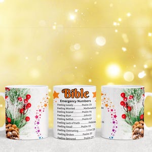 May include: Two white ceramic mugs with a winter holiday design. One mug has a Bible verse list with the title "Emergency Numbers". The list includes verses for feelings like loneliness, worry, fear, hurt, selfishness, lack of faith, smallness, untrusting, brokenness, and betrayal.