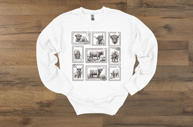 May include: White long-sleeve sweatshirt featuring a collection of Highland cow illustrations designed as postage stamps. The black and white drawings depict various poses of the cows, creating a unique and artistic design.