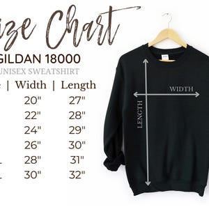 May include: A black Gildan 18000 unisex sweatshirt hangs on a wooden hanger. The image includes a size chart with measurements in inches for sizes S through 3XL. The chart shows the width and length of the sweatshirt.