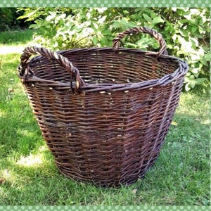 Può includere: Un grande cesto di vimini marrone con due manici. Il cesto è seduto su un letto di erba verde.