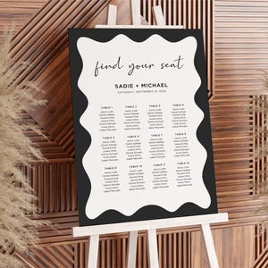 May include: Black and white wedding seating chart with the text "find your seat" and "Sadie + Michael" with the date "Saturday, September 16, 2023". The chart is on a white easel.