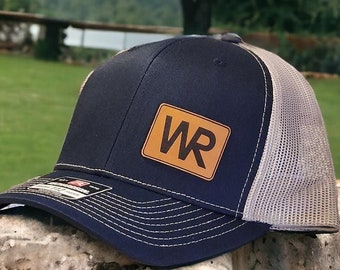 May include: A navy blue and gray trucker hat with a brown leather patch that says "WR" on it.
