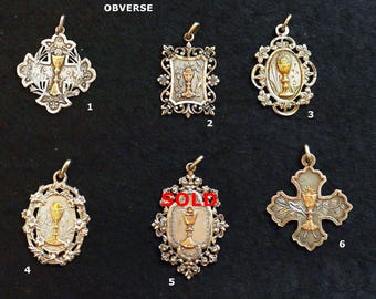 May include: A collection of six vintage religious pendants, each featuring a chalice design. The pendants are in various shapes, including crosses and ovals, with ornate detailing and gold-tone accents. The word "OBVERSE" is at the top.