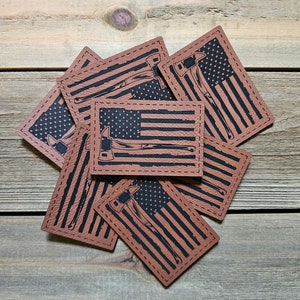 May include: A stack of six brown leather patches with an American flag design and a black axe graphic. The patches have a stitched border.