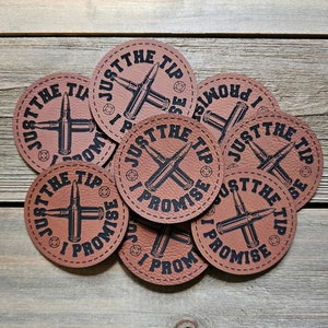 May include: Eight brown leather coasters with a black and white design. Each coaster features a crossed bullet design with the text "Just the tip I promise" around the edge.