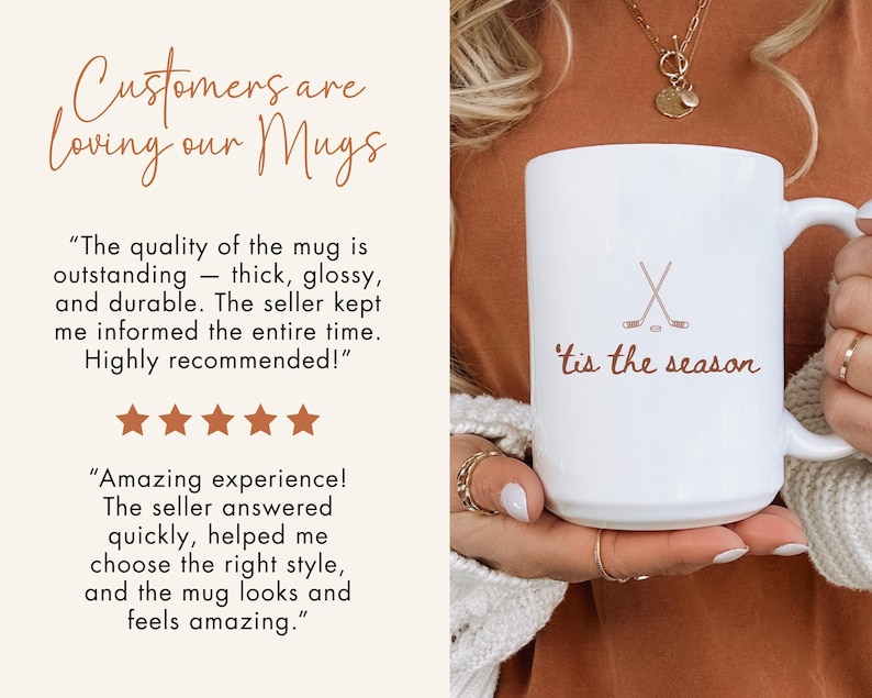 May include: White ceramic mug featuring the text "'tis the season" and crossed hockey sticks. The mug has a handle and is held by a person. The image also includes customer reviews and the phrase "Customers are loving our Mugs".