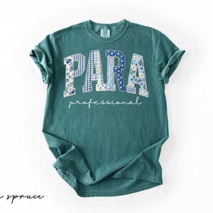 May include: A teal-colored t-shirt with the word "PARA" in large, patchwork-style letters, featuring blue floral and gingham patterns. Below, the word "professional" is written in a cursive font. The shirt is labeled "blue spruce" in the bottom left corner.