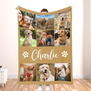 May include: A tan fleece blanket featuring a collage of nine photos of a golden retriever. The name "Charlie" is written in white script below the photos, with paw prints on either side. The blanket is held up by a person.