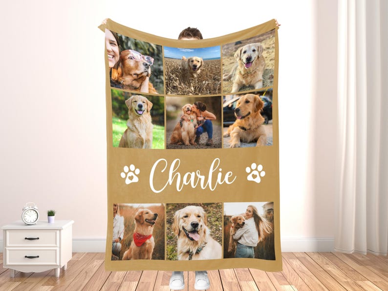 May include: A tan fleece blanket featuring a collage of nine photos of a golden retriever. The name "Charlie" is written in white script below the photos, with paw prints on either side. The blanket is held up by a person.