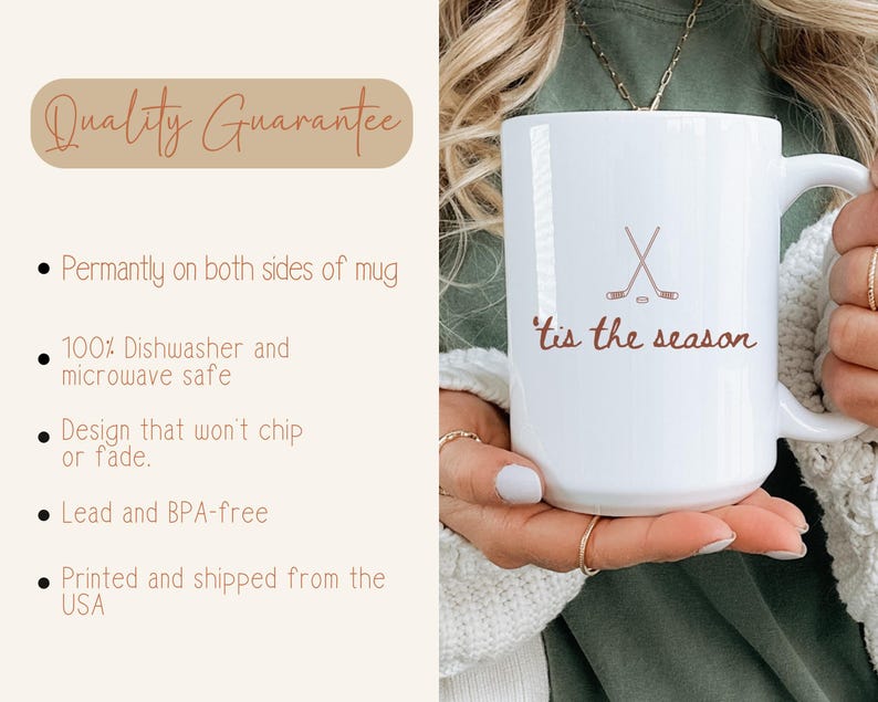 May include: White ceramic mug featuring a hockey stick and puck design, with the words "tis the season" in brown script. The mug has a large handle and is held by a person.