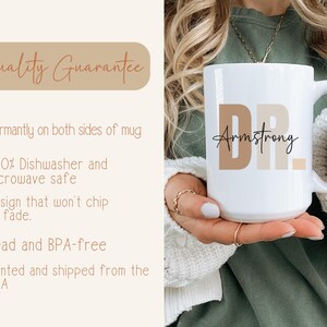May include: White ceramic mug with the text "DR. Armstrong" in brown lettering. The mug is being held by a person's hand.
