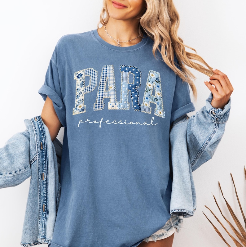 May include: A blue t-shirt with the word "PARA" in patchwork letters, featuring floral and gingham patterns. Below, the word "professional" is written in a cursive font. The shirt is worn with a denim jacket.