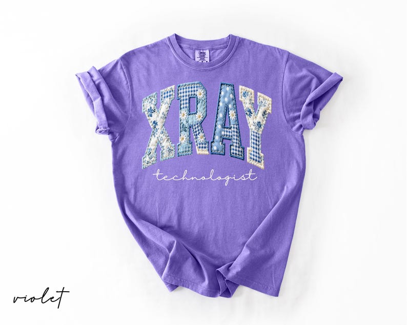 May include: A violet-colored t-shirt with the word "XRAY" in a patchwork design of floral and gingham patterns. The word "technologist" is written in a script font below the word "XRAY".