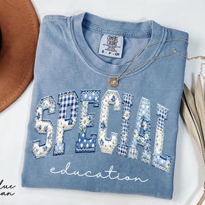 May include: A white ceramic mug with a black handle and the text "But First, Coffee" in a black, handwritten-style font. The mug is on a white surface.