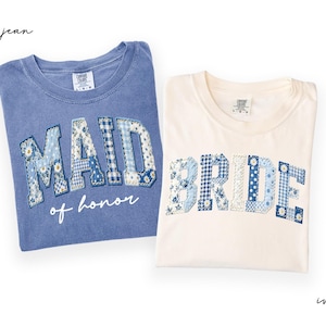 May include: Two t-shirts, one blue and one ivory, with text. The blue shirt says "MAID of honor" in patchwork letters. The ivory shirt says "BRIDE" in patchwork letters. The patchwork letters have floral and gingham patterns.