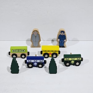 以下が含まれることがあります： 緑色の車両、黄色の車両、青色の車両、緑色の車両、グレーのスーツを着た男性、青いオーバーオールを着た男性など、木製列車の車両とフィギュアのセット。列車の車両は車輪が付いており、さまざまなデザインで塗装されています。フィギュアは直立しており、顔と服が描かれています。