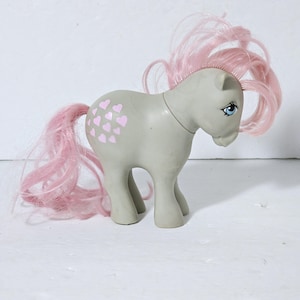 May include: A gray My Little Pony with pink hair and a heart pattern on its flank.